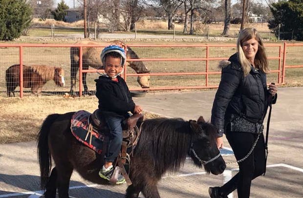 Child on a pony led by a person