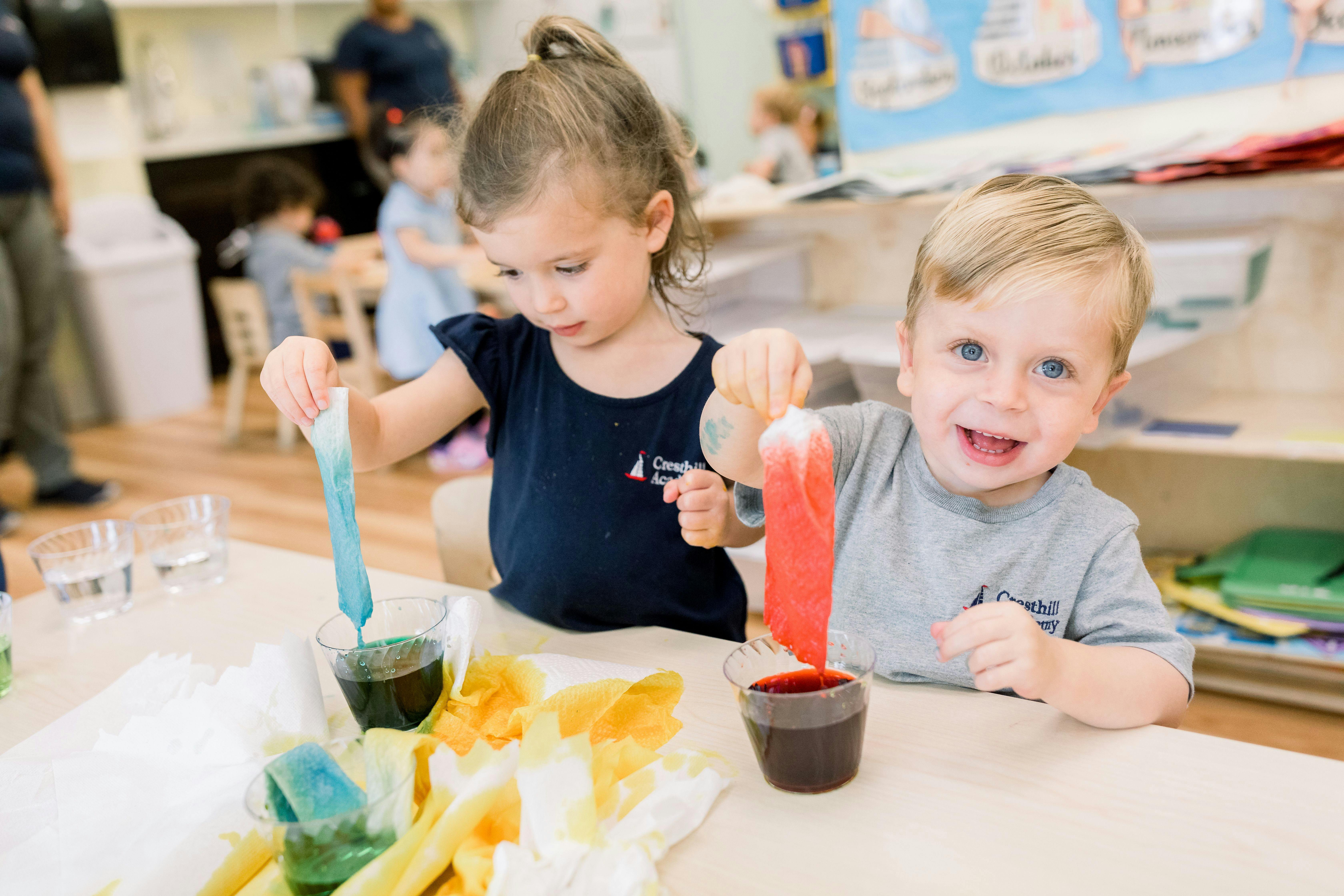 Two children at a table doing a science experiment with colored liquids
