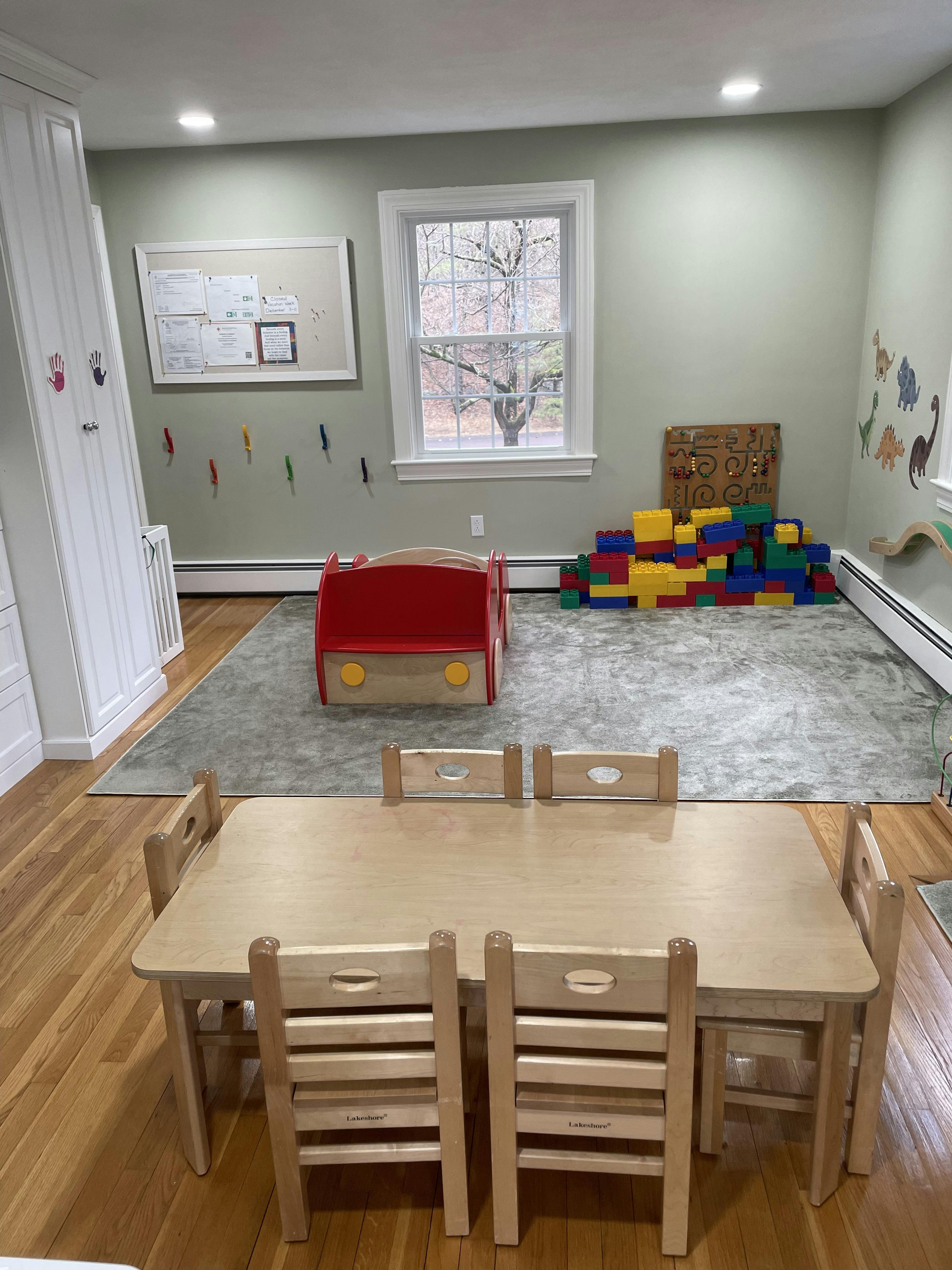 Children's classroom with small wooden table and chairs, red toy car, and building blocks