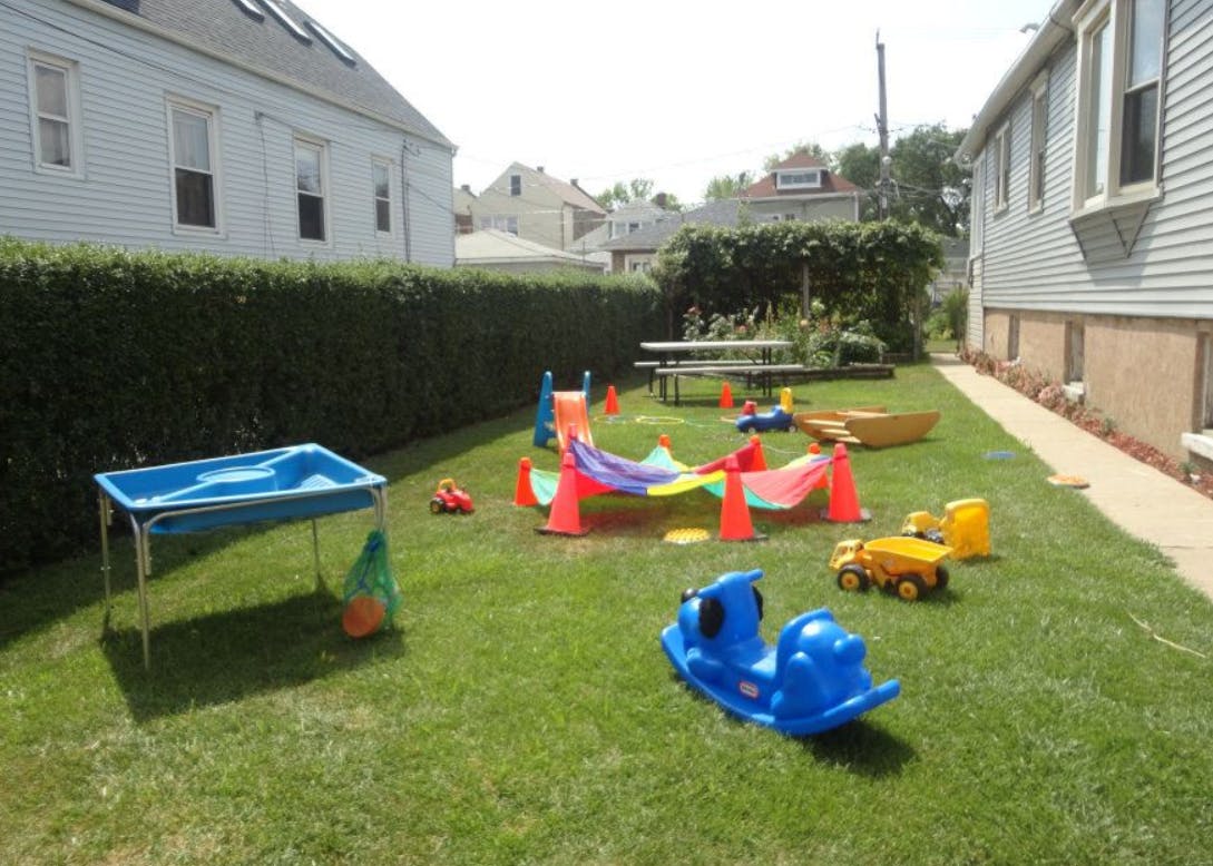 Outdoor play area with various colorful toys on green grass