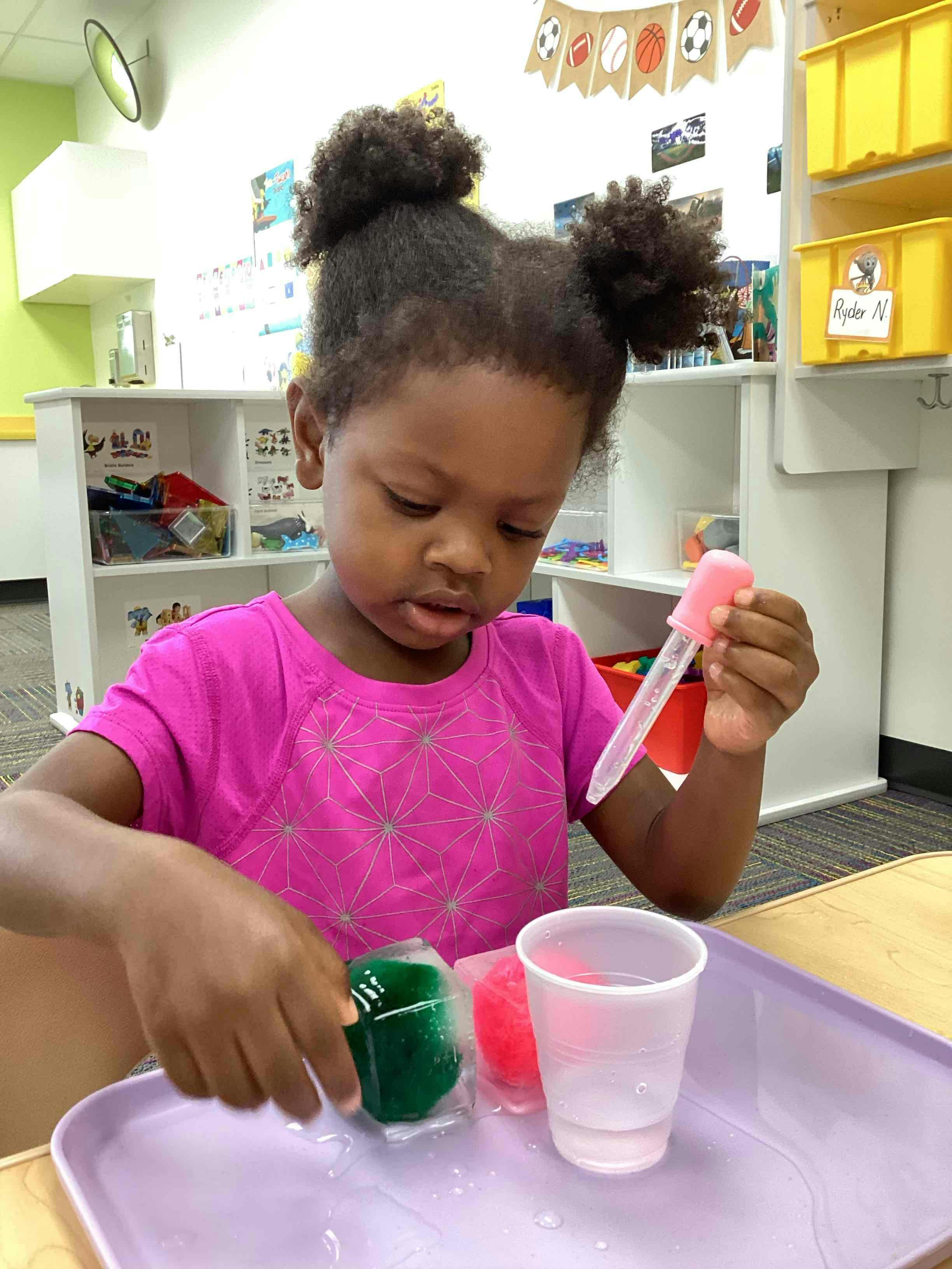 Child playing with ice and a dropper