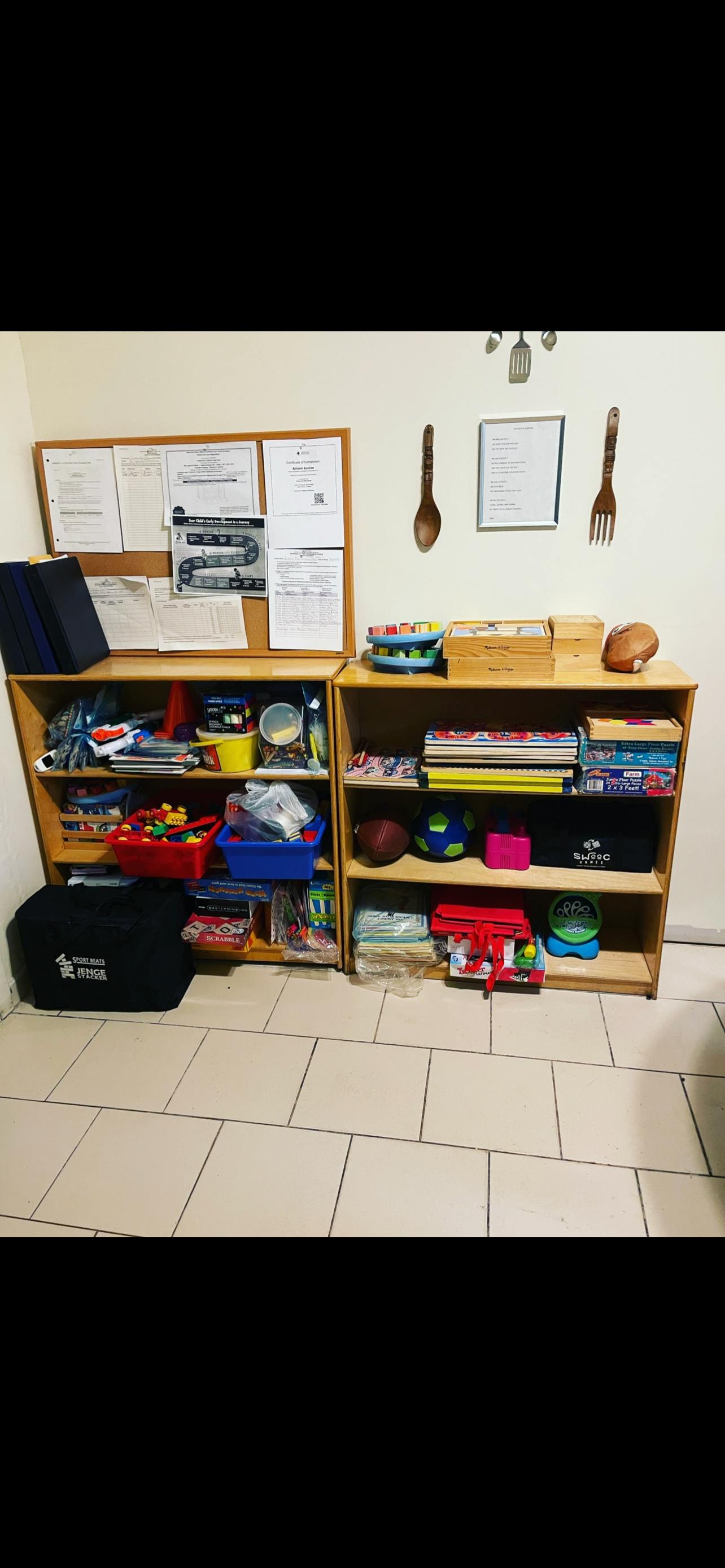Two wooden shelves filled with various items next to a bulletin board