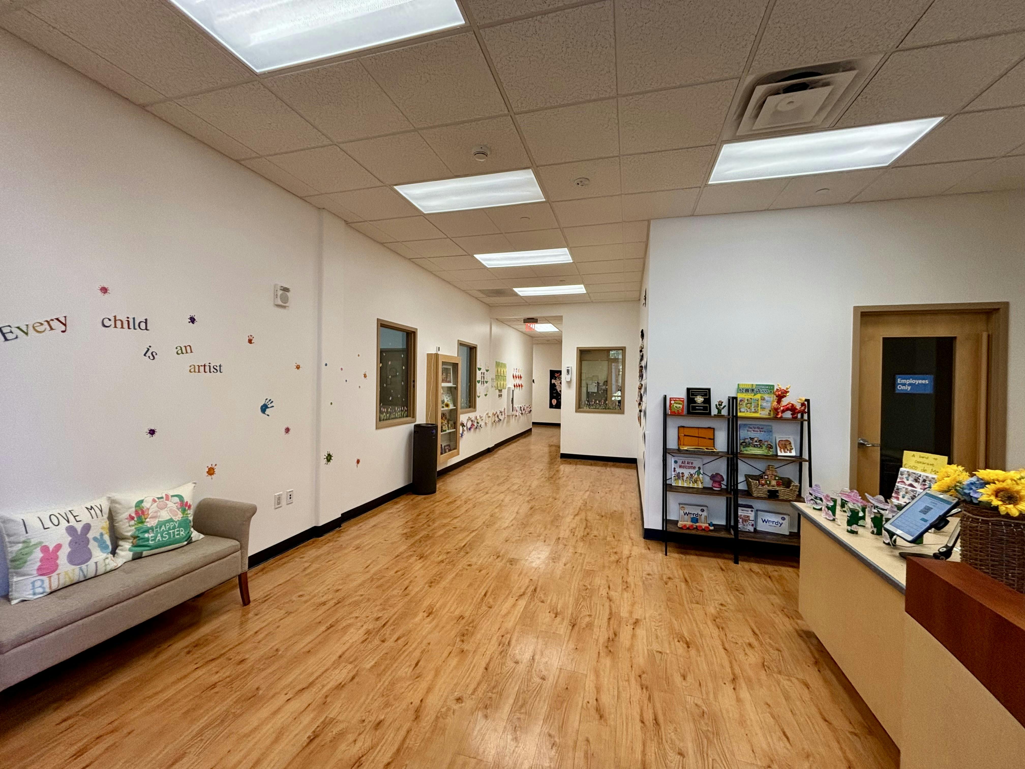 Long hallway with wood floors, a couch, and a reception desk