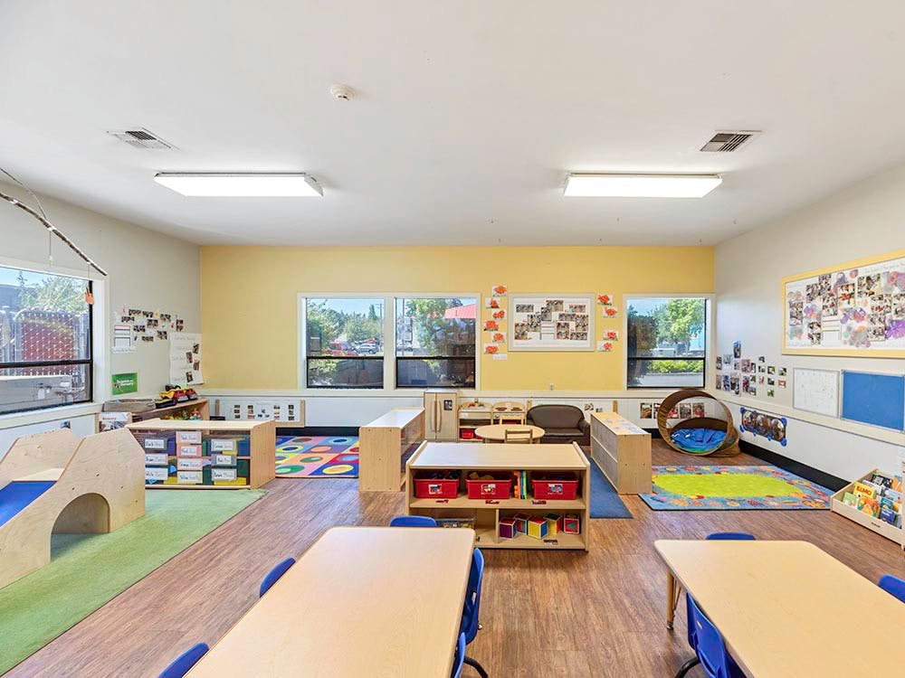 Empty colorful children's classroom with small tables and play areas