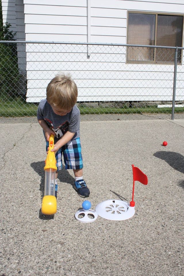 Child playing with a toy golf club and ball