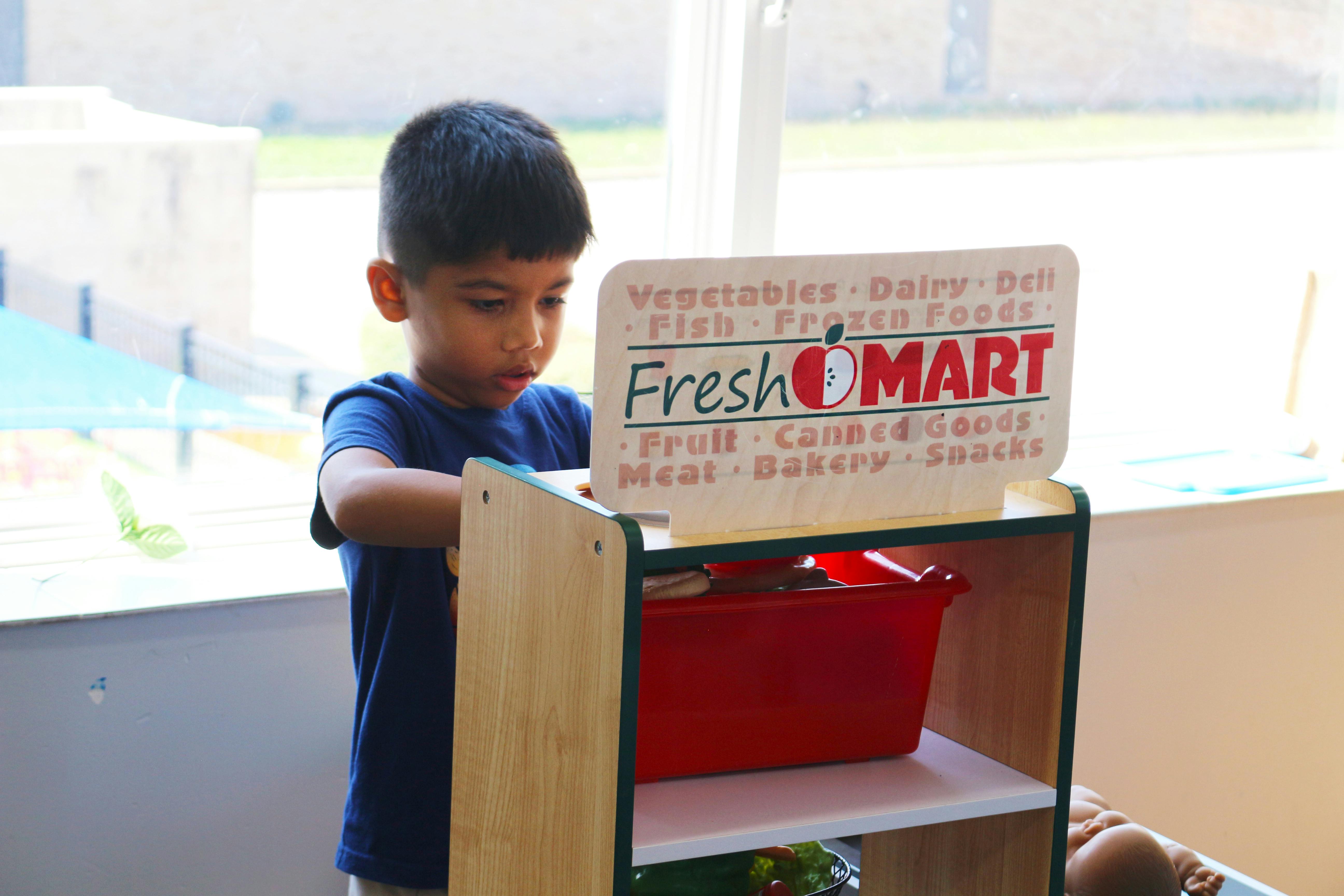 Child playing with a FreshOMart toy stand