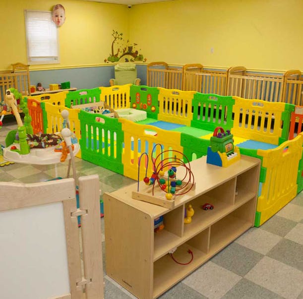 Play area with colorful fences, toys, and cribs in the background