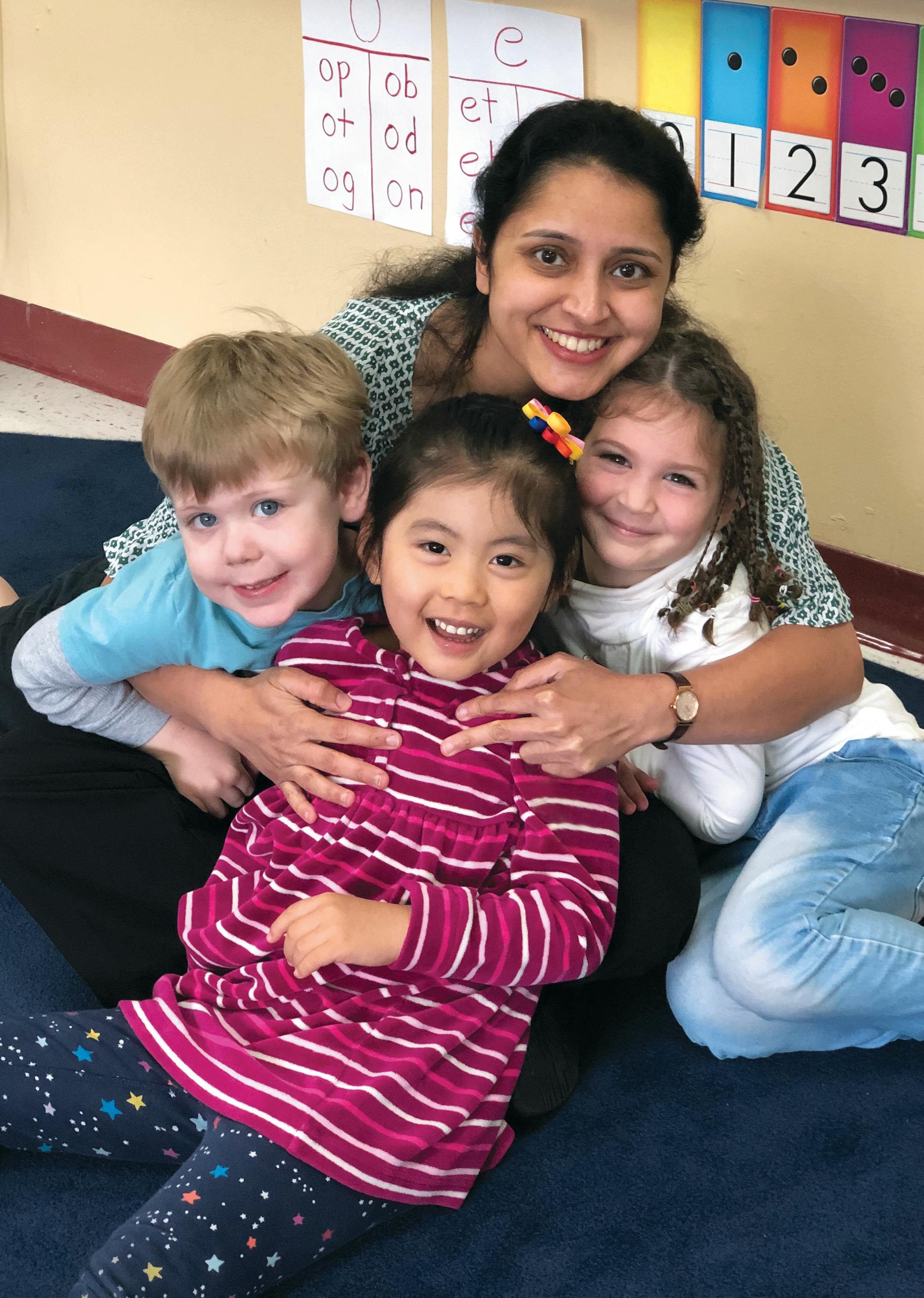 Person with three children in a classroom