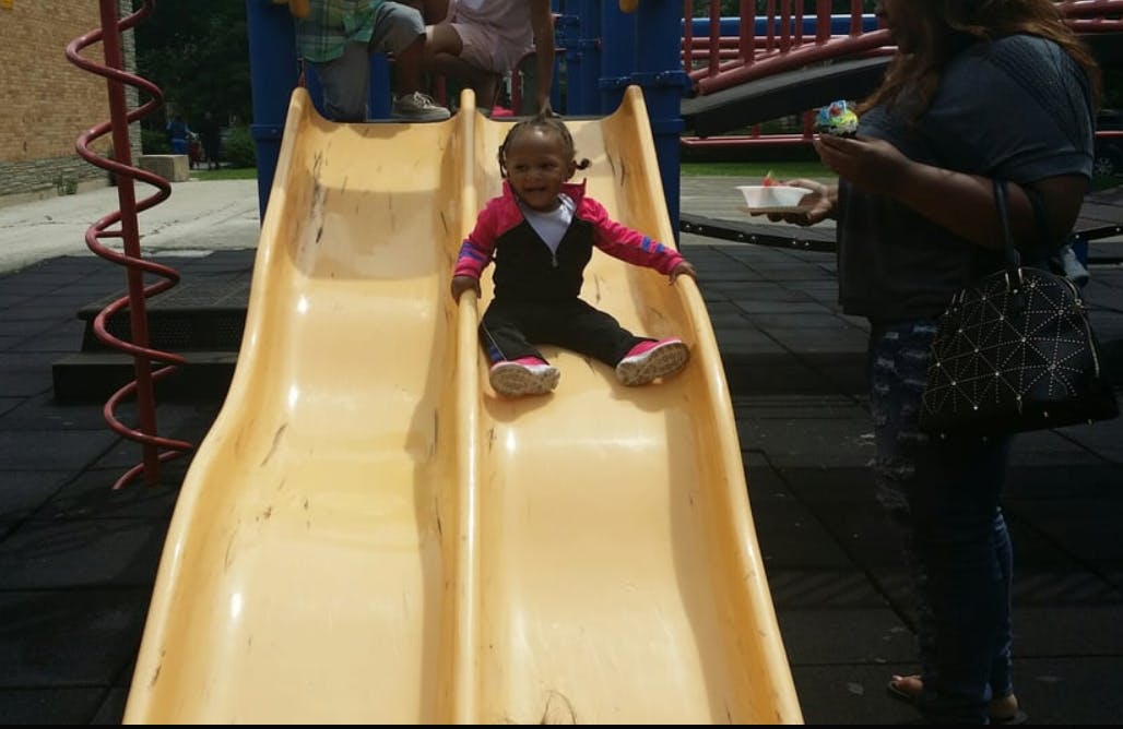 Child sitting on a yellow playground slide