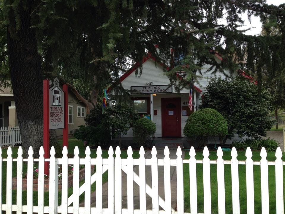White picket fence in front of a building with a red door