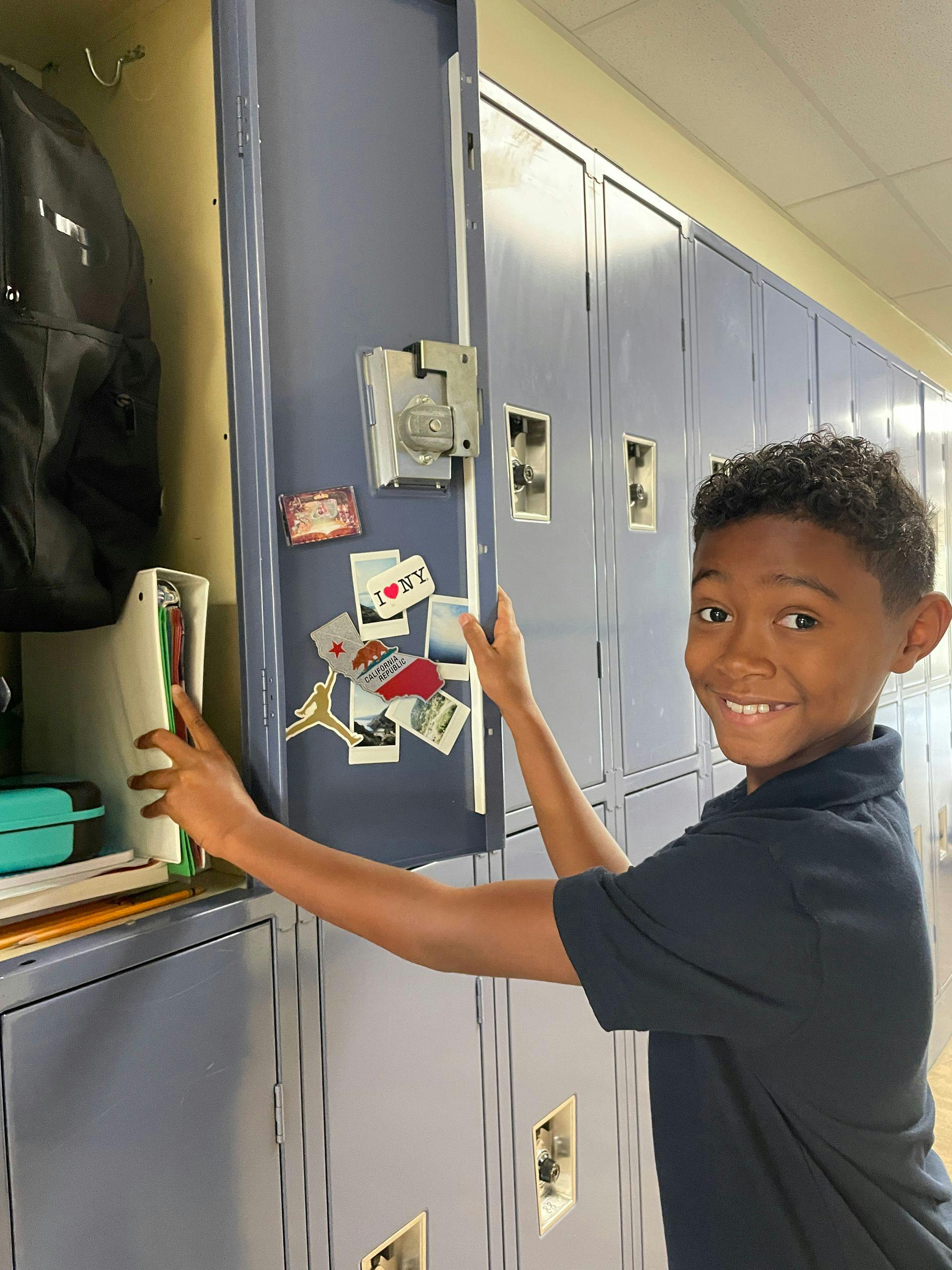Child smiling while opening a locker in a hallway