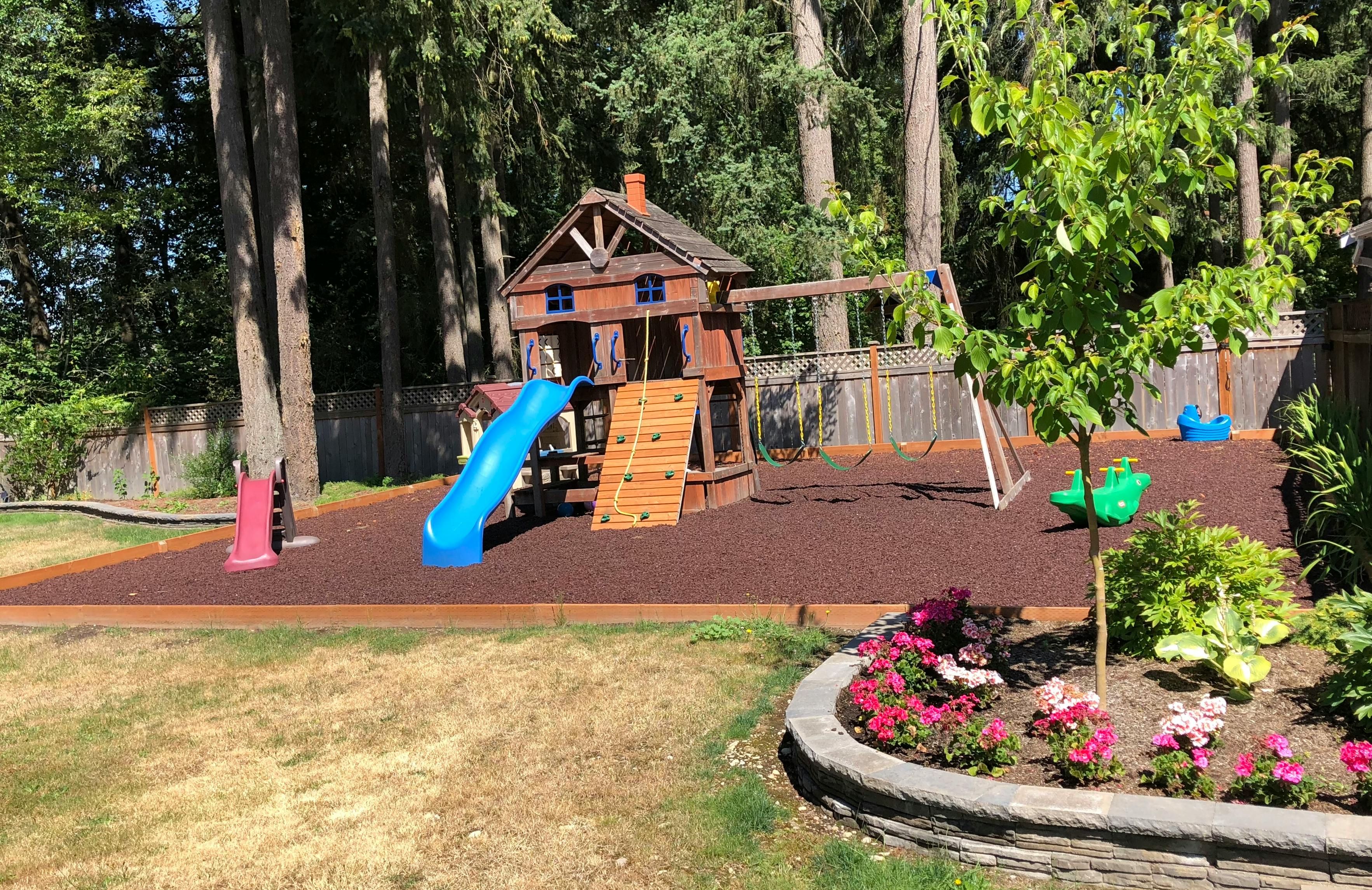 Playground with a wooden playhouse, blue slide, and swings