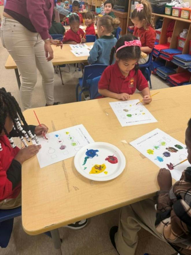 Children painting at desks in a classroom