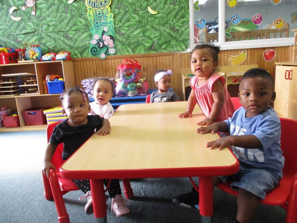 Four children sitting at a table in a classroom