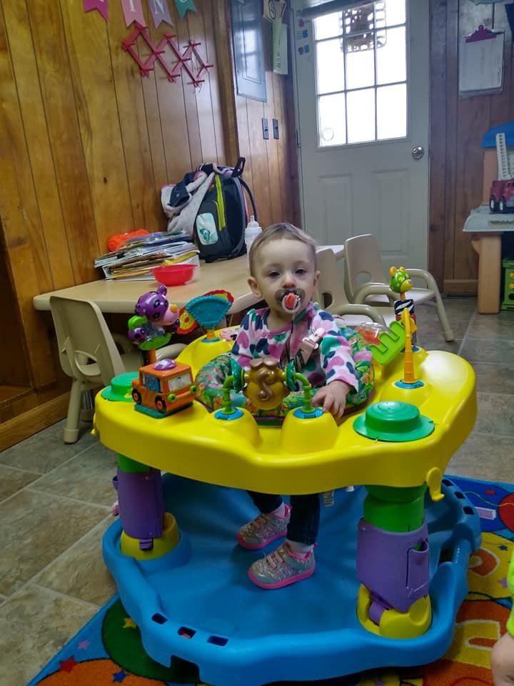Child with a pacifier in a baby activity center