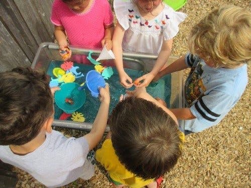 Children playing with water and toys in a sensory bin