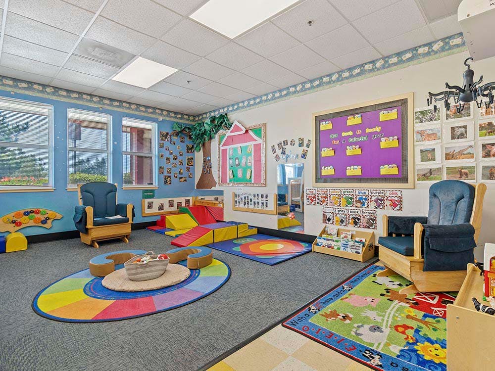 Colorful classroom with play mats, two rocking chairs, and decorated walls