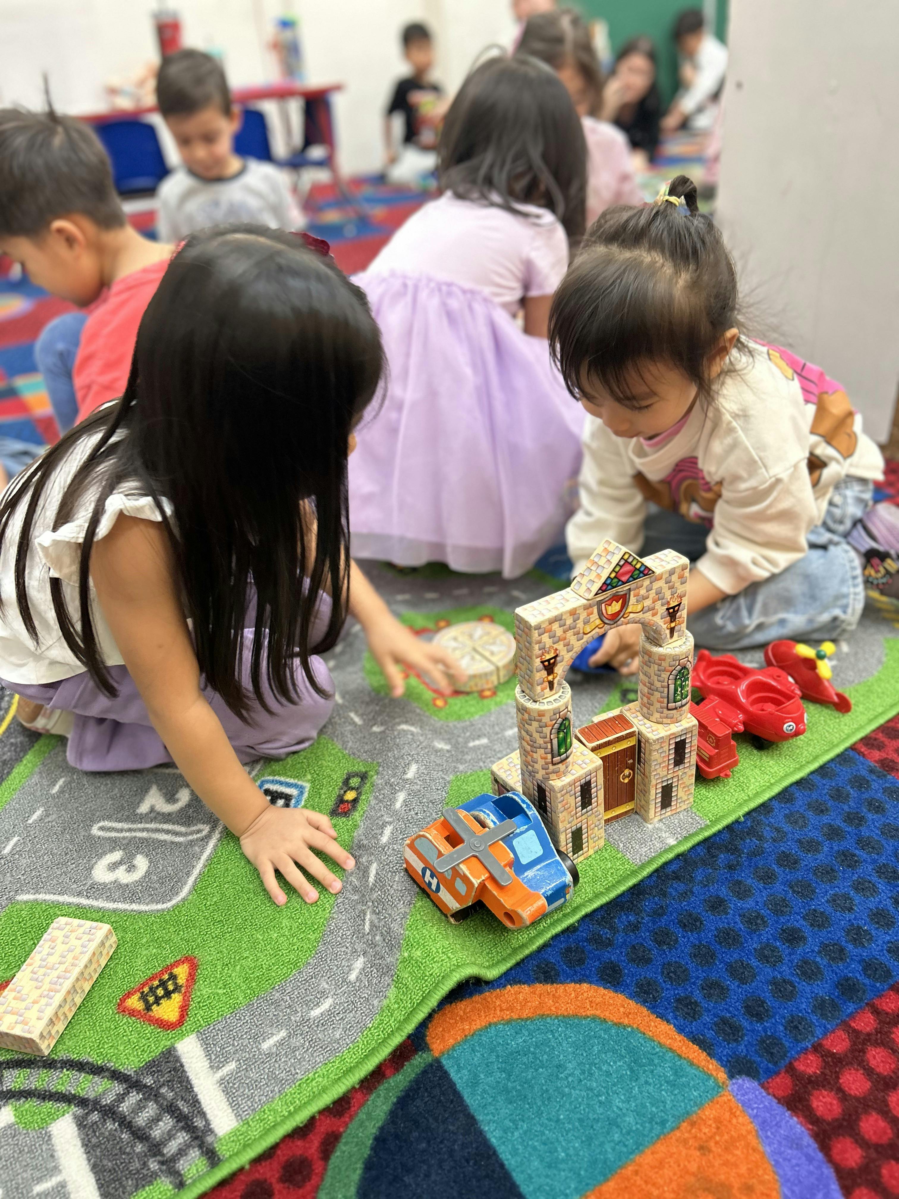 Children playing with toy blocks and vehicles on a play rug