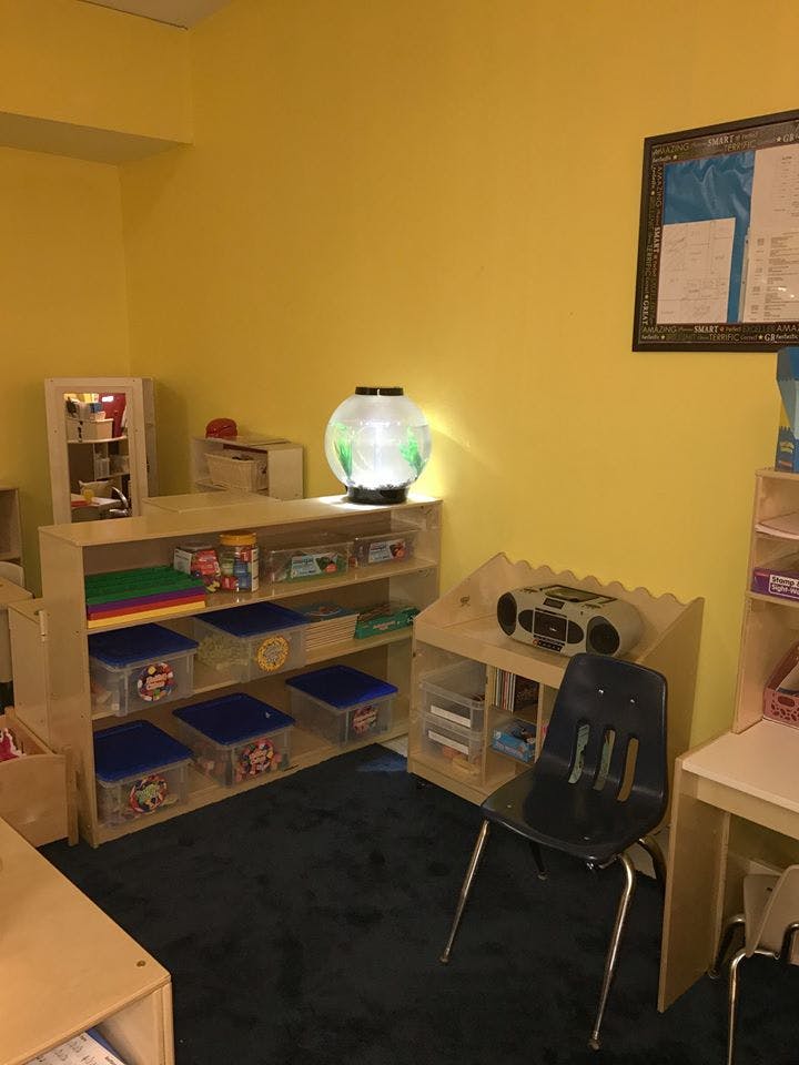 Classroom with shelves of toys and supplies, a chair, and a fishbowl