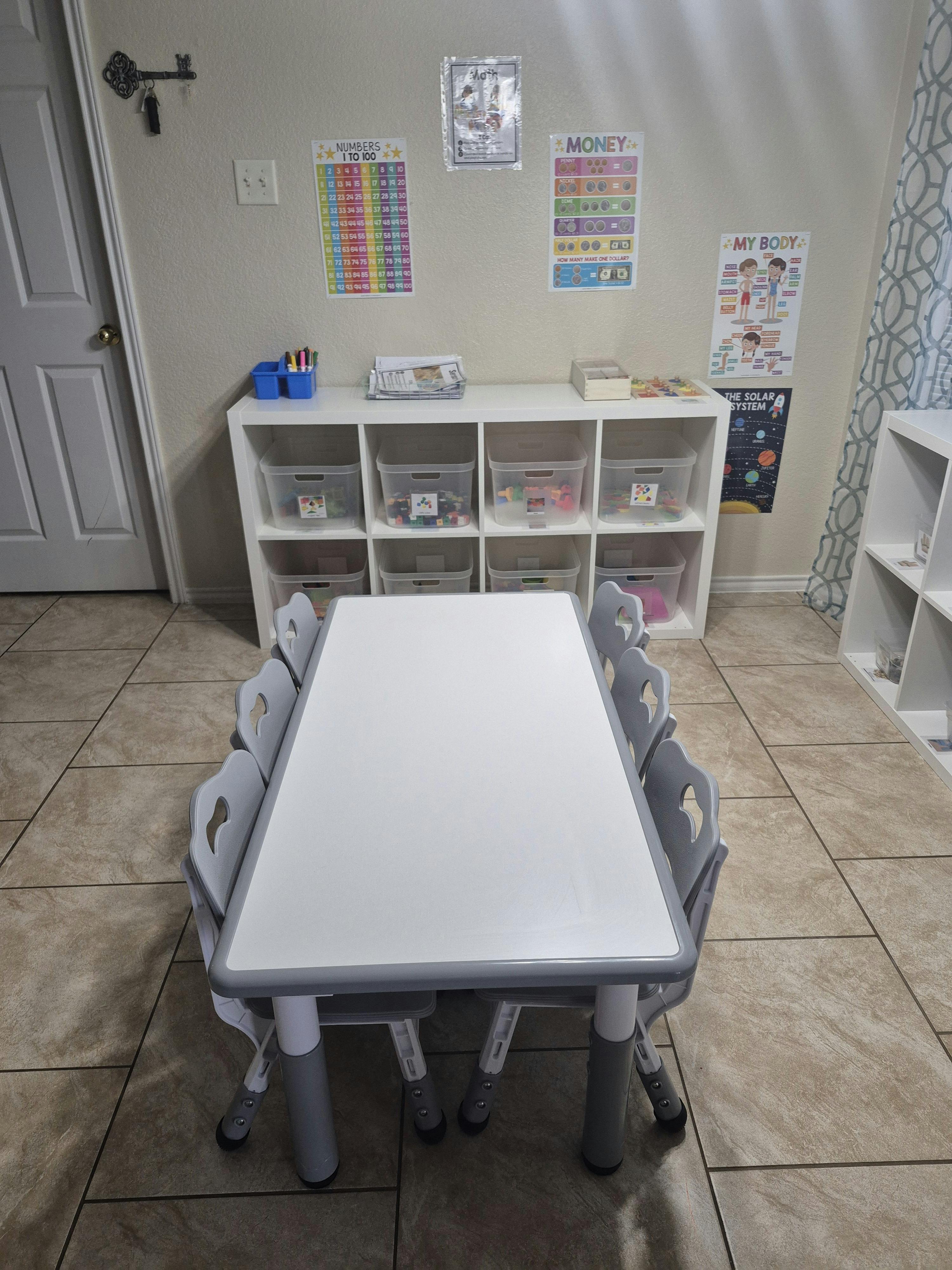 Children's classroom with a white table, chairs, and educational posters
