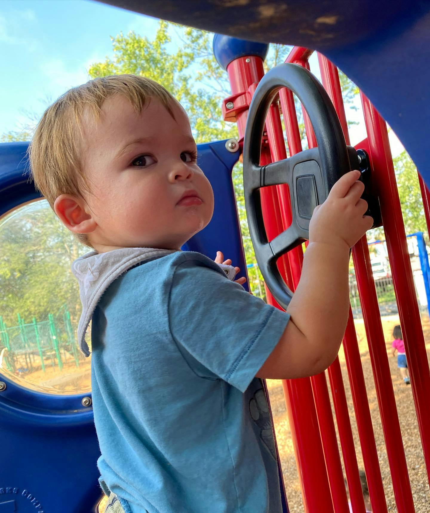 Child playing with a steering wheel on a playground structure