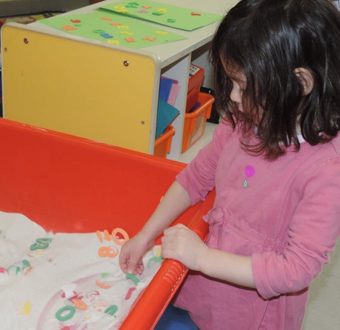 Child playing with colorful letters in a classroom