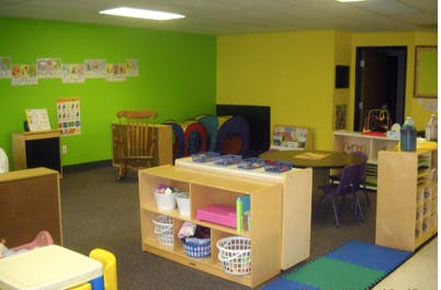 Playroom with green and yellow walls, shelves, and small tables