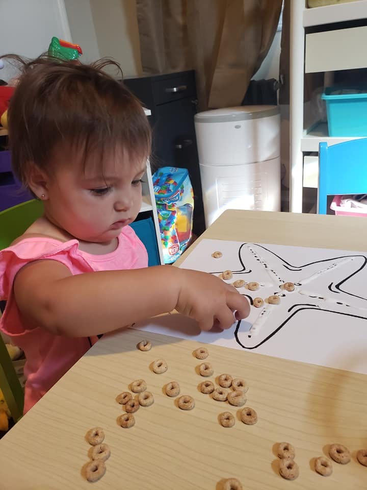 Child placing cereal O's on a starfish outline