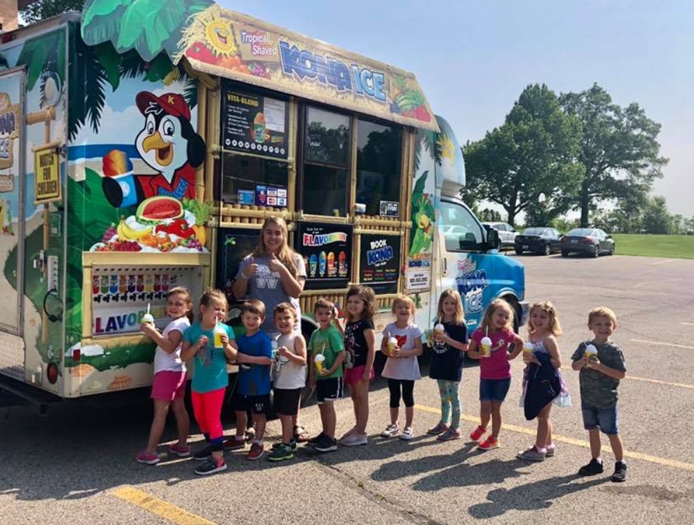 Person and children standing in front of a colorful food truck