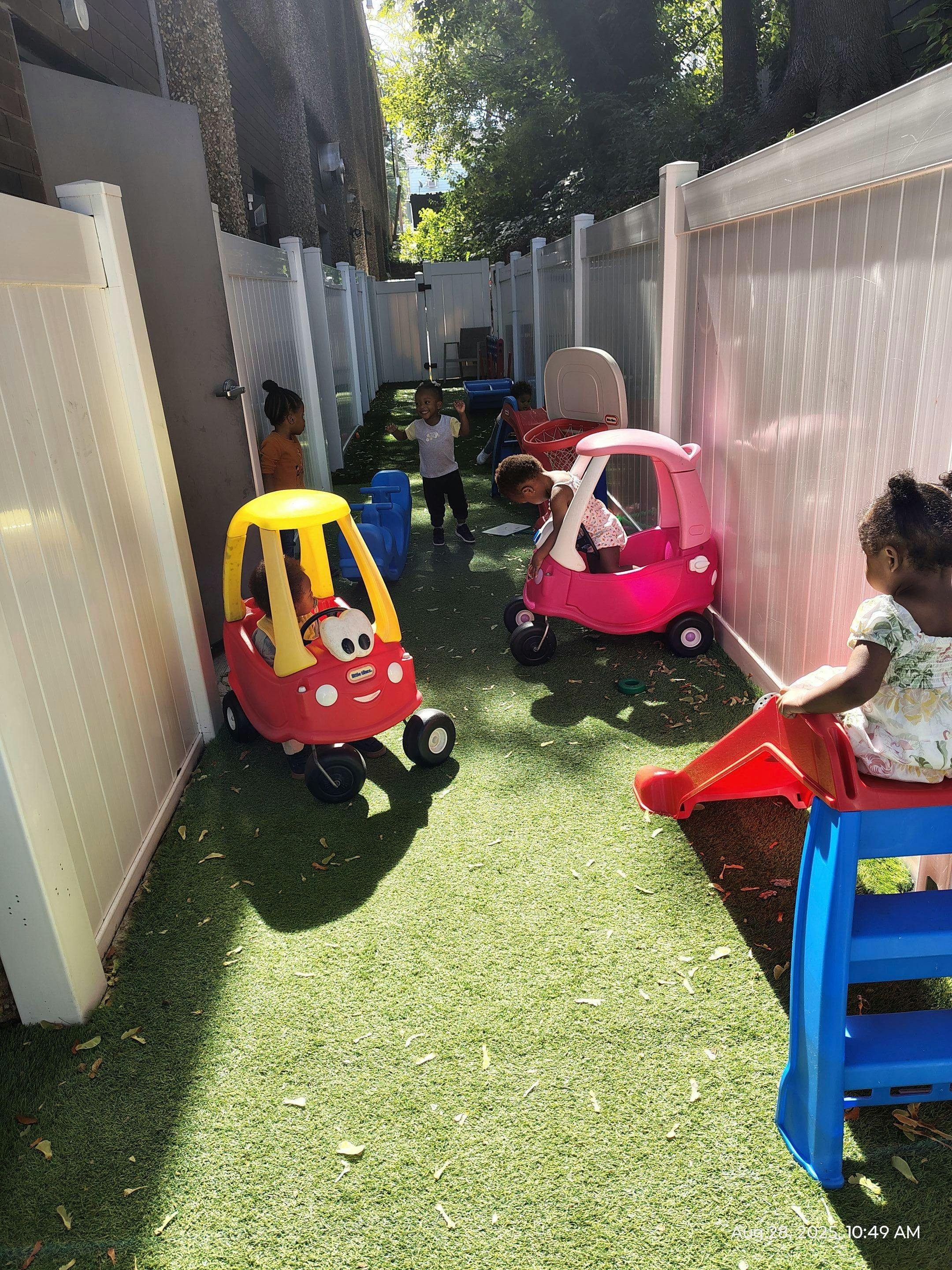 Children playing with toy cars and a slide in an outdoor area