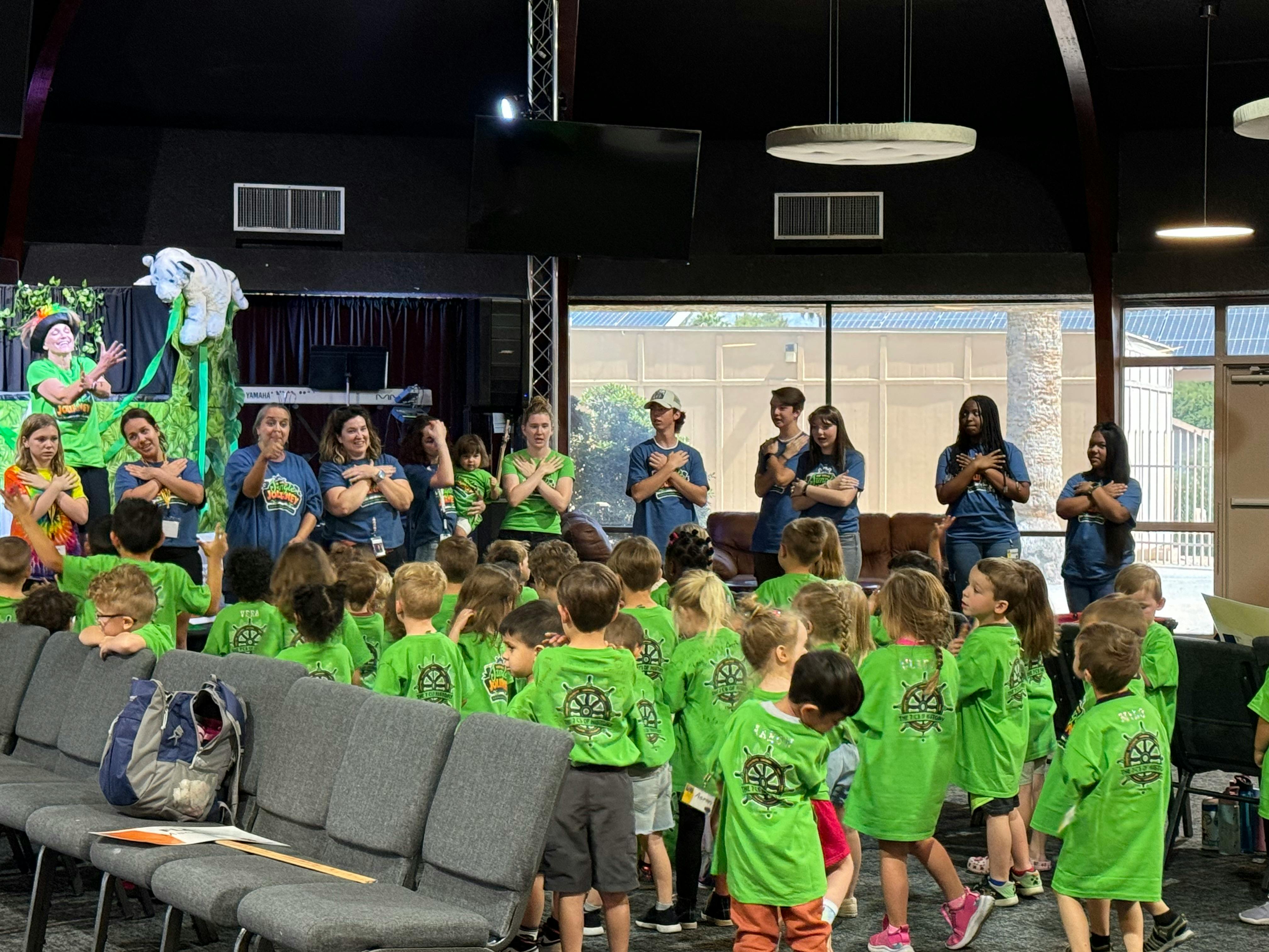 Adults and children in green shirts standing in a room