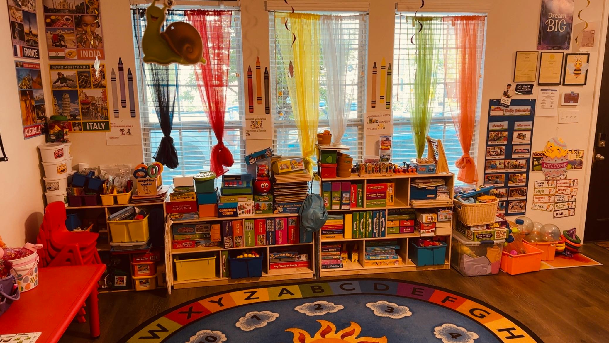 Classroom with colorful curtains, bookshelves, and a sun rug