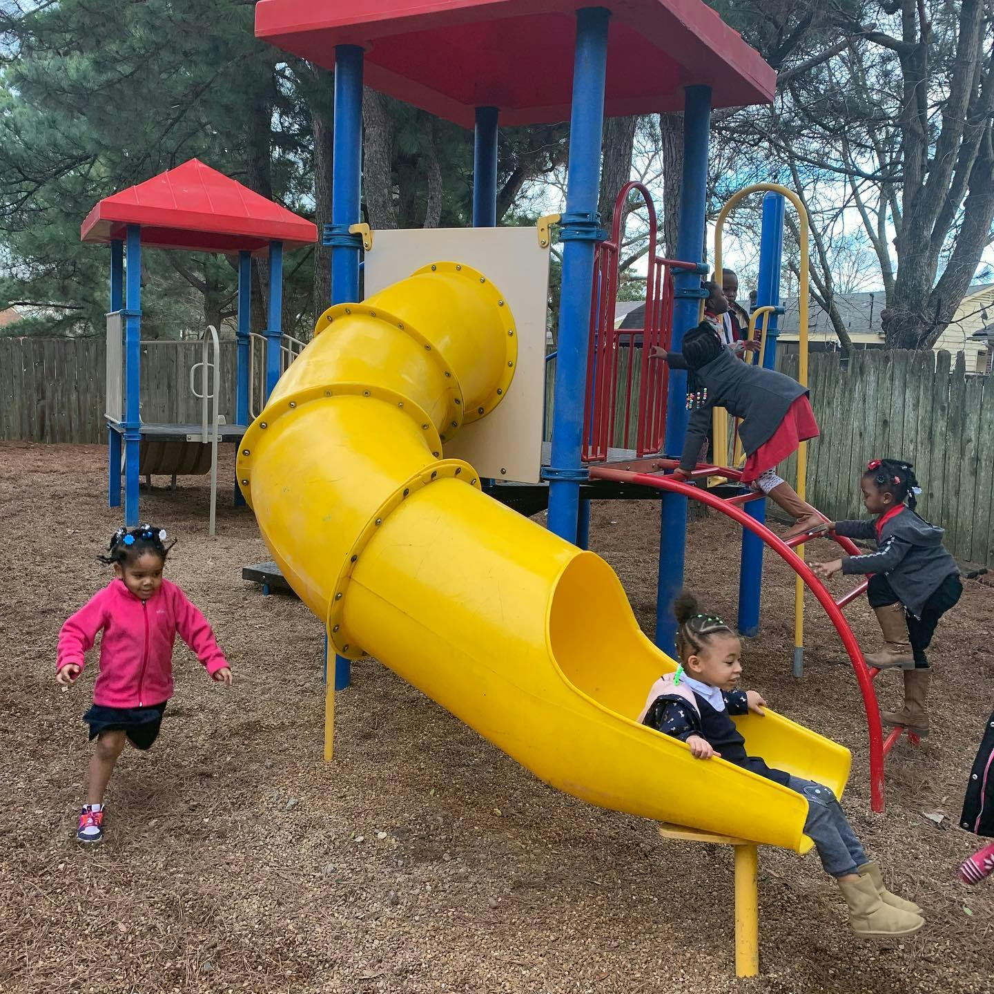 Children playing on a yellow slide and playground equipment