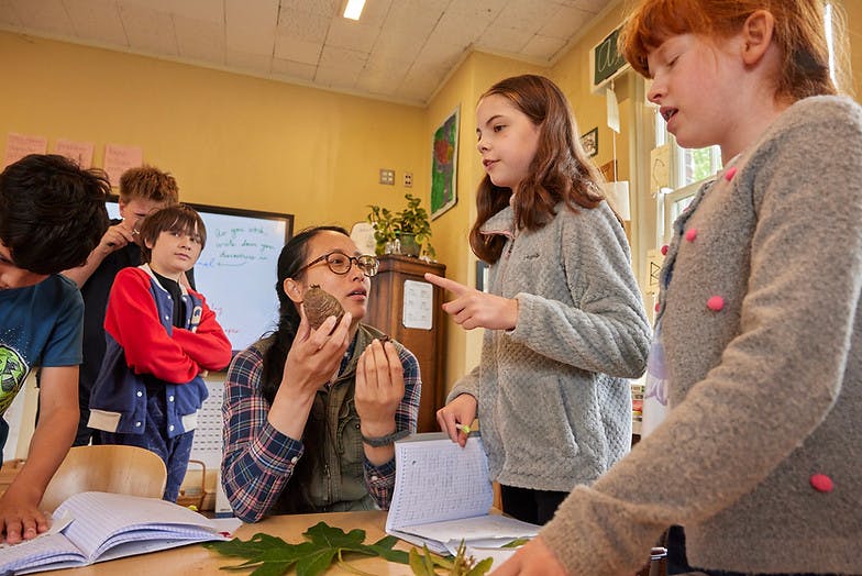 Adult and children in a classroom examining natural objects