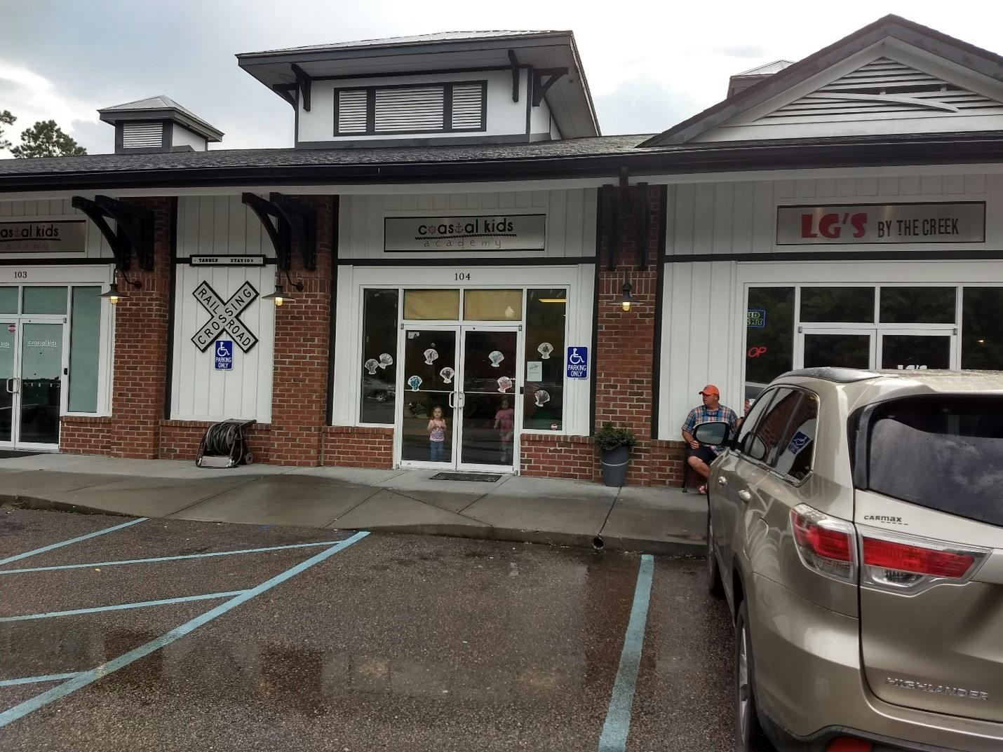 Retail storefronts with 'COASTAL KIDS academy' and 'LG'S BY THE CREEK' signs