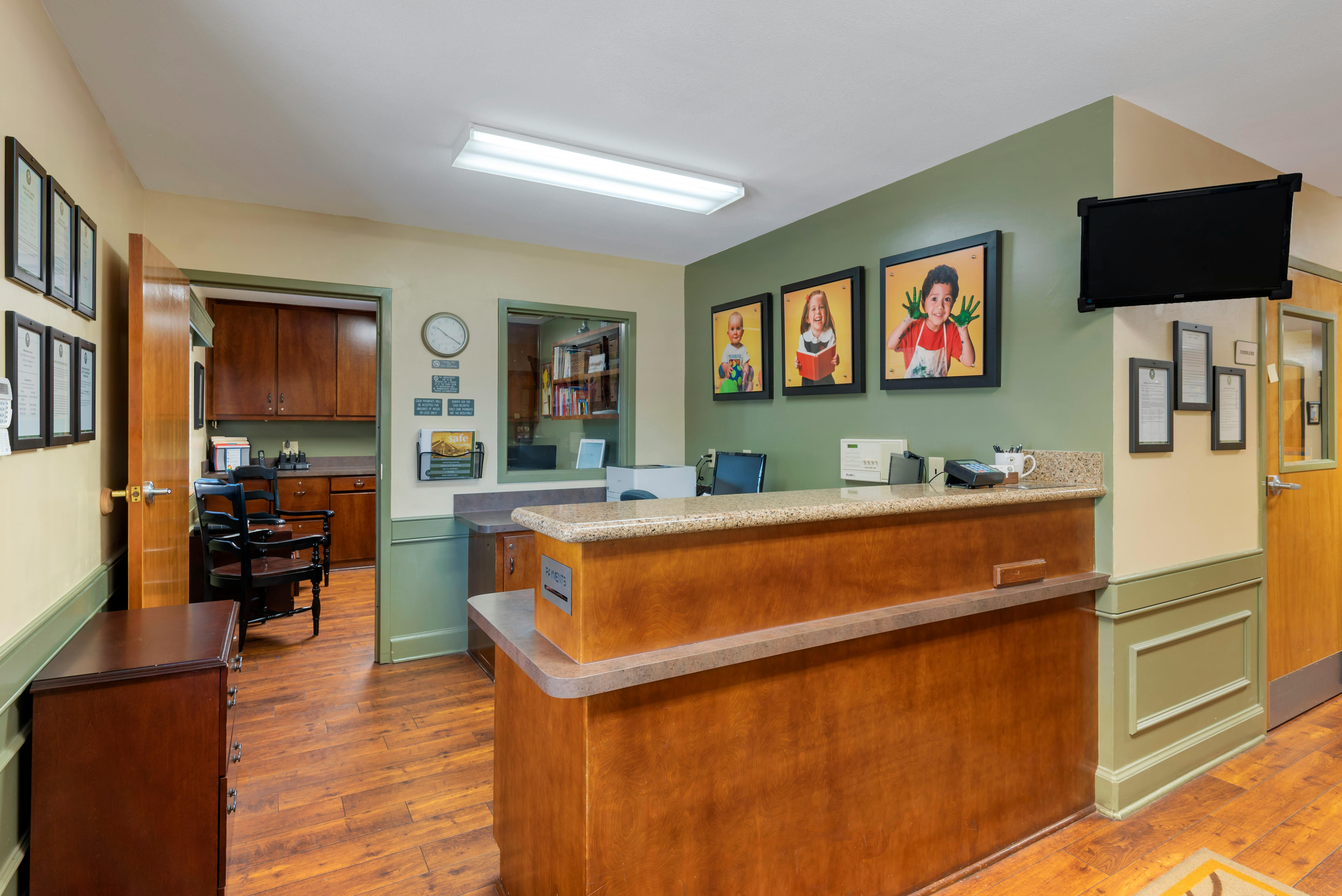 Reception desk with office equipment, children's photos on wall, open door to back room