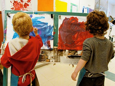 Two children painting on easels in a classroom