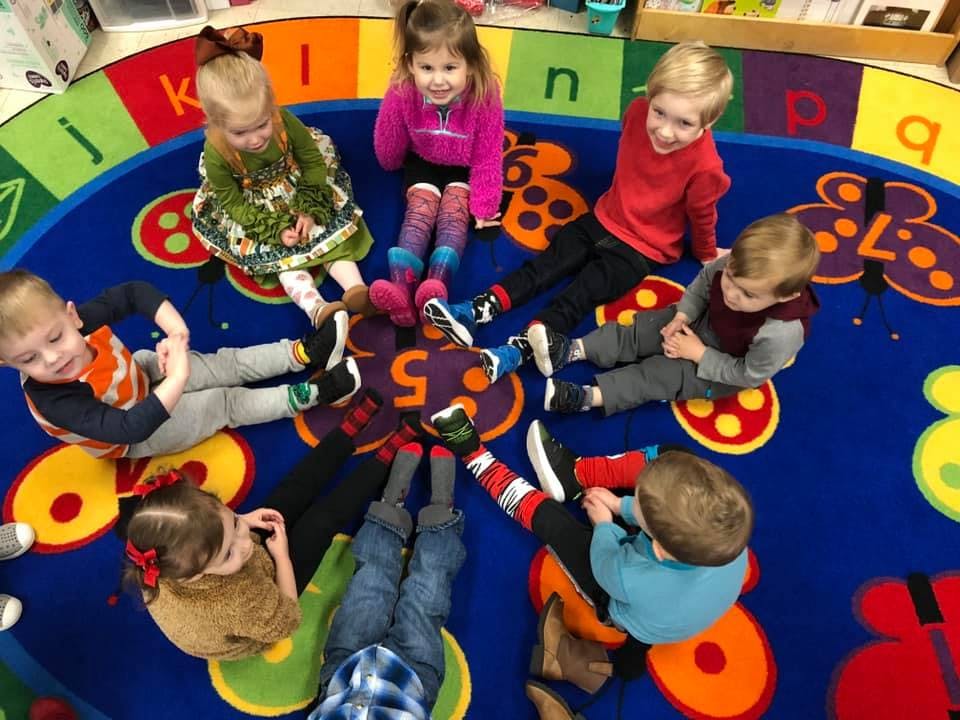Children sitting on a colorful rug in a classroom