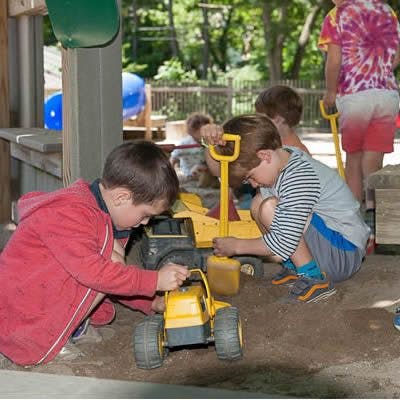 Children playing with toy trucks in a sandbox