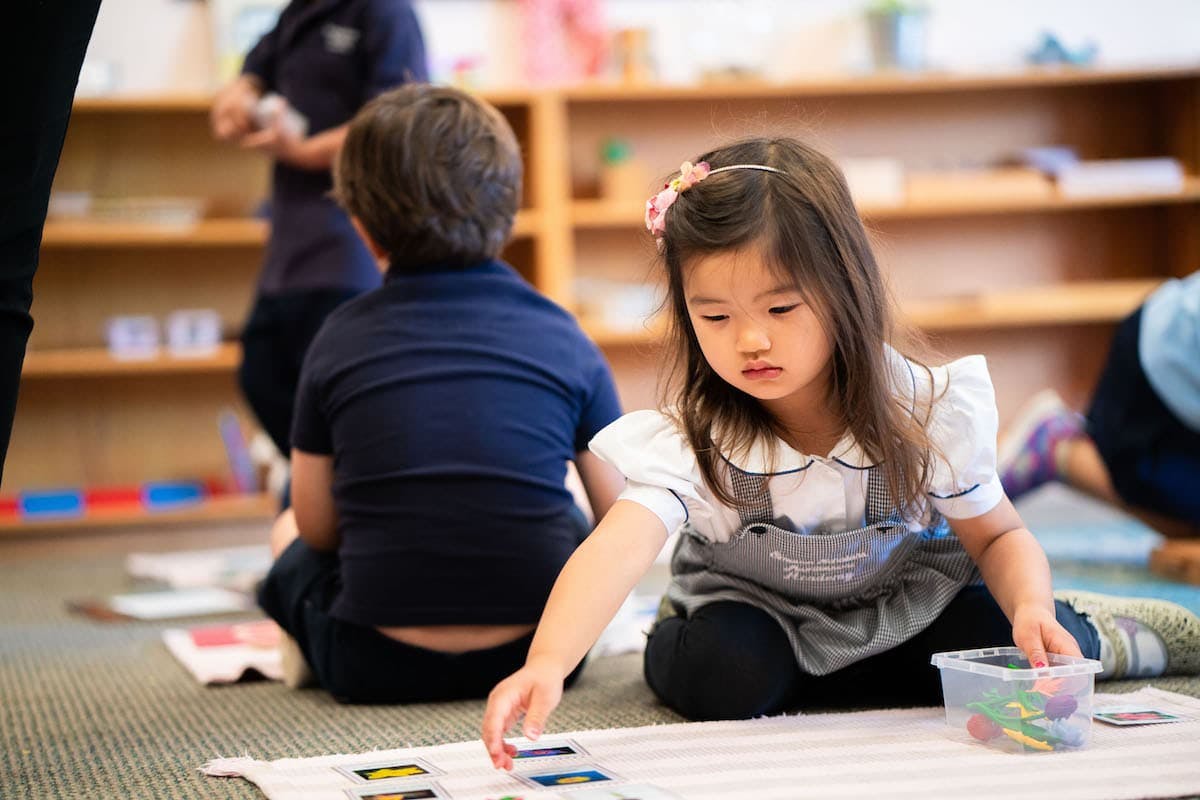 Child on floor playing with small items from a container