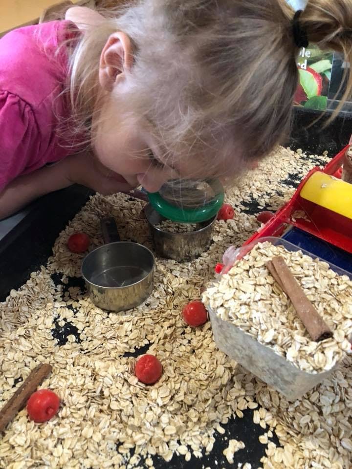 Child looking into a small container filled with oats