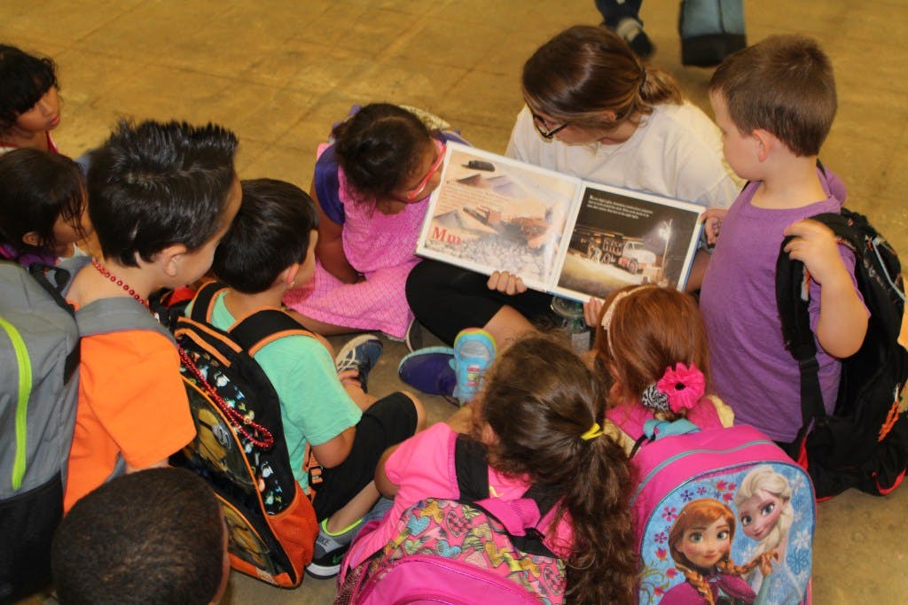 Adult reading a book to a group of children