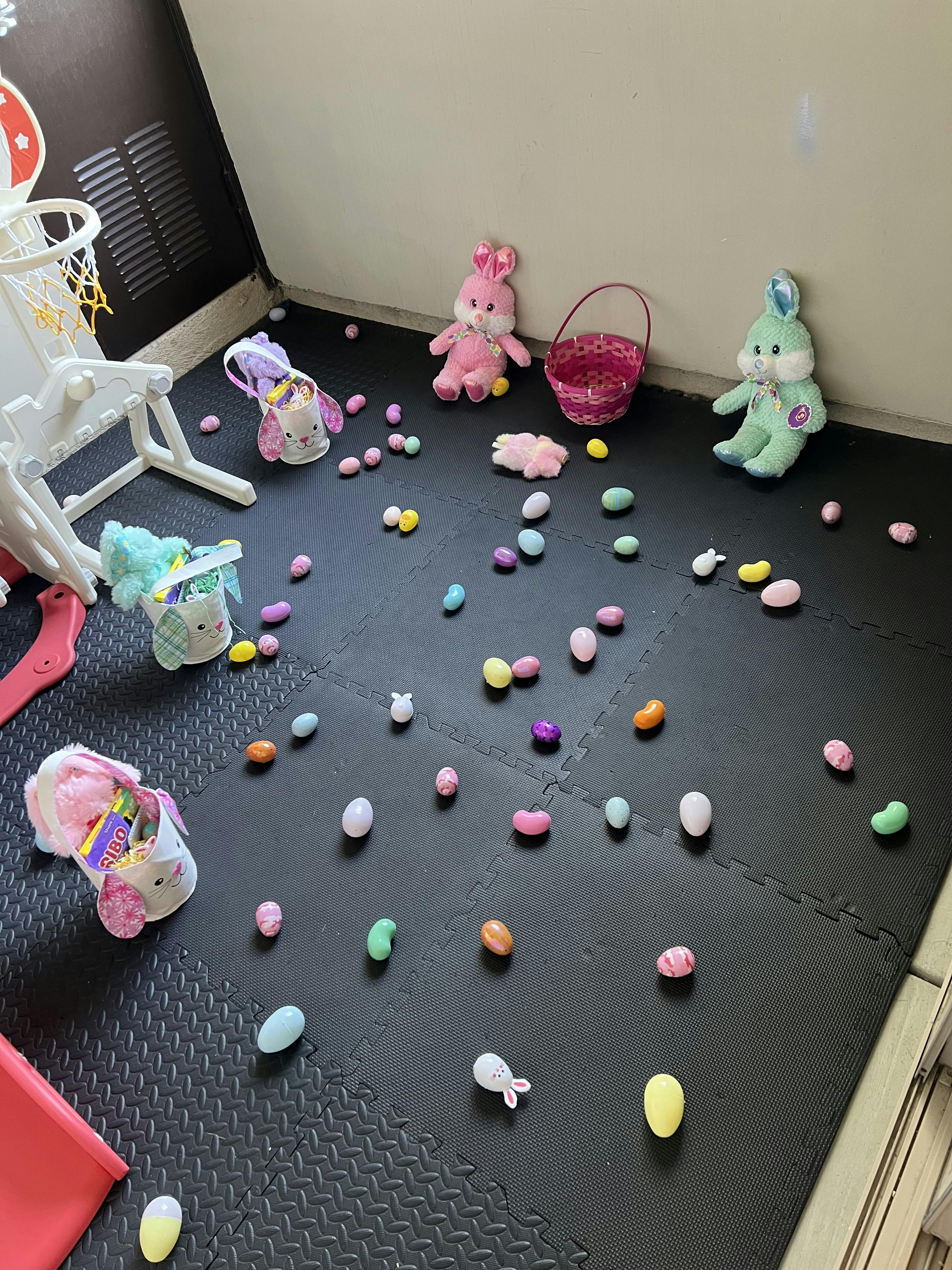 Easter eggs, bunny baskets, and stuffed bunnies on a black floor