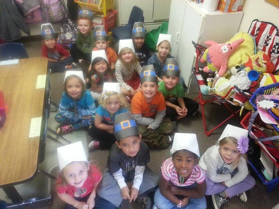 Group of children wearing pilgrim hats sitting on the floor