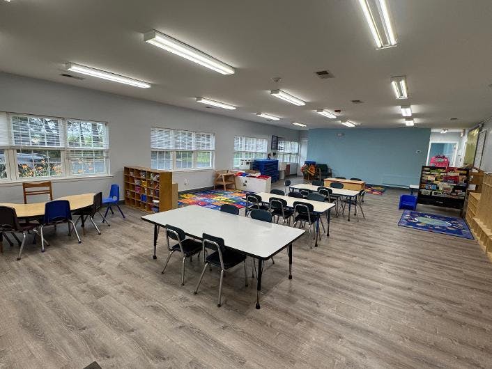 Empty preschool classroom with small tables and chairs