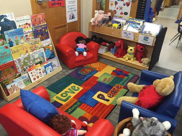 Children's reading corner with small chairs, a colorful rug, and bookshelves