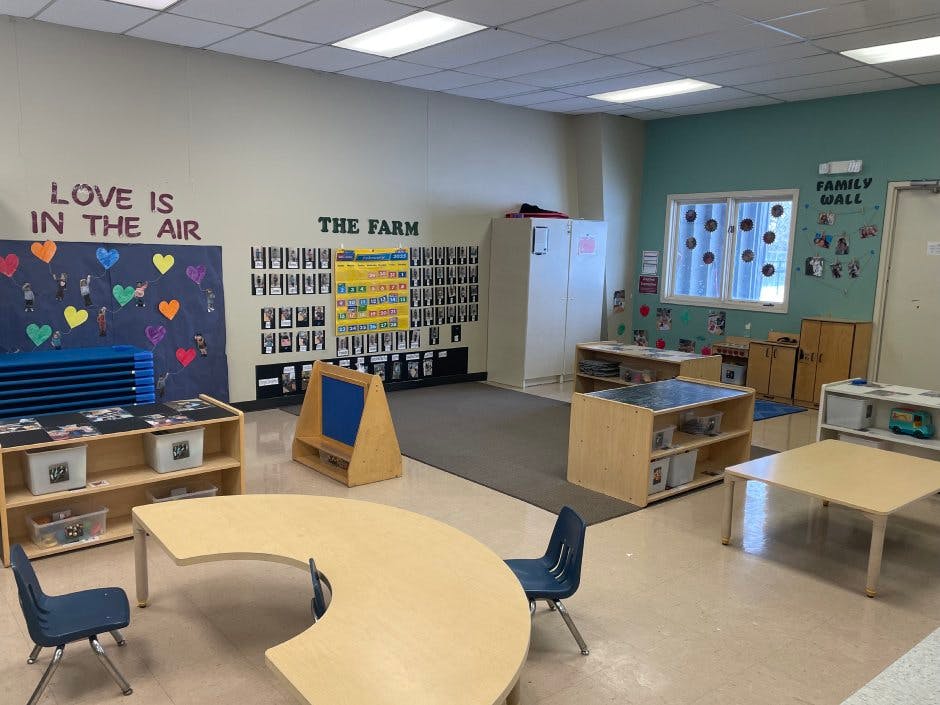 Classroom with tables, chairs, shelving, and wall decorations