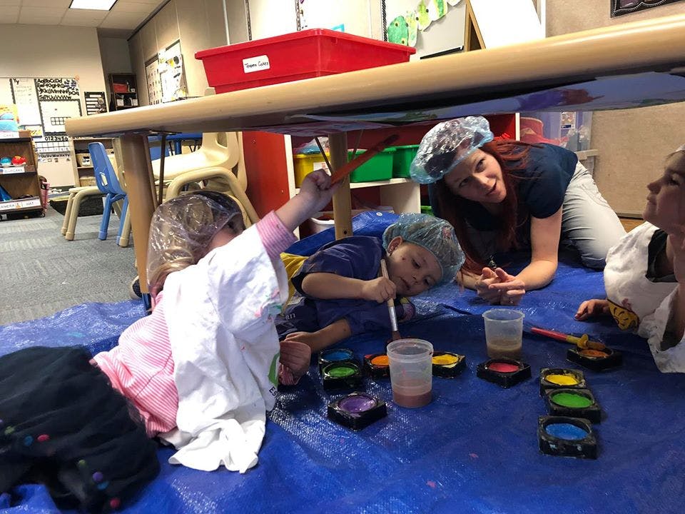 Adults and children painting under a table