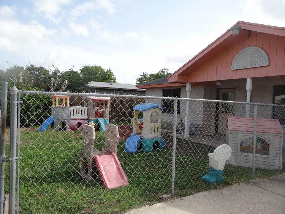 Playground with slides and playhouses behind a chain link fence