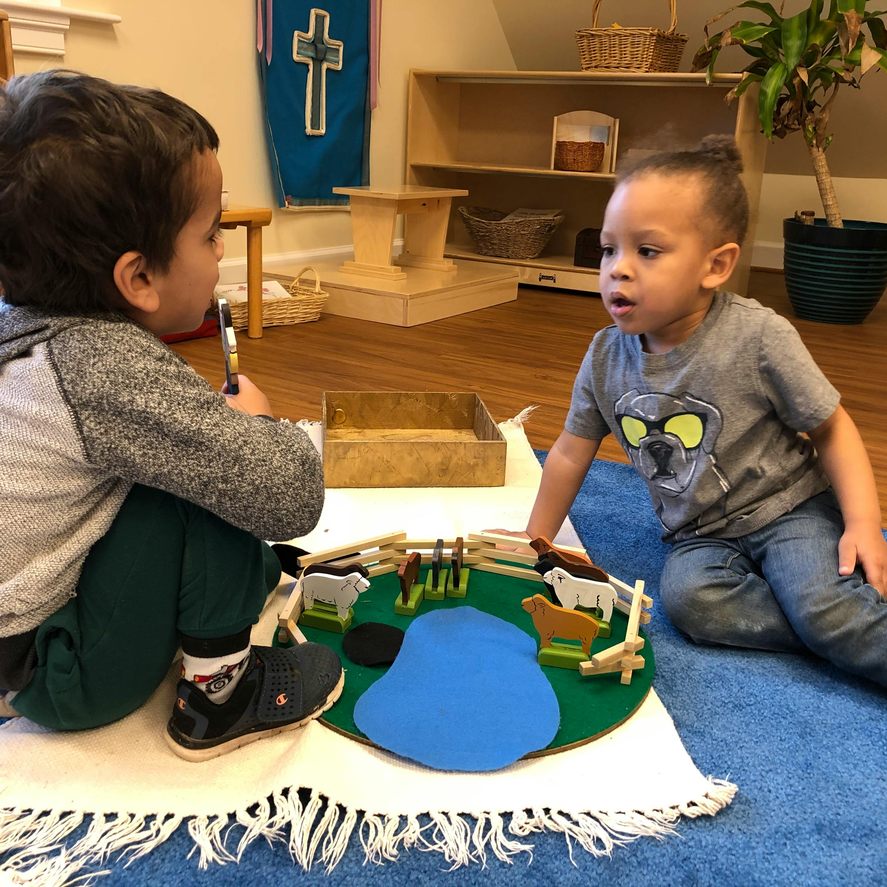 Two children playing with a felt mat and animal figures